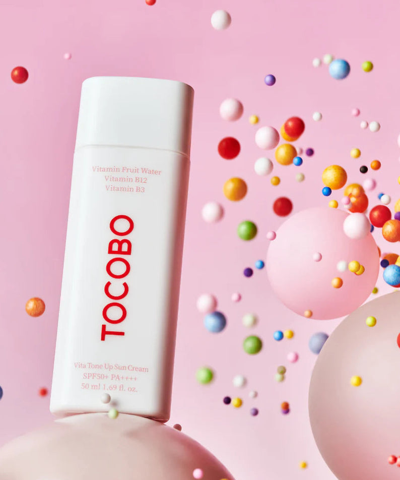 TOCOBO Vita Tone Up Sun Cream 50ml, crème solaire sur fond rose avec billes colorées, style cosmétique en studio