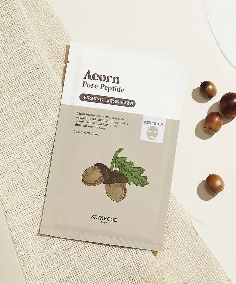 SKINFOOD Acorn Pore Peptide Firming Mask, sachet sur fond textile clair, mise en scène avec motifs noisette en coquille.