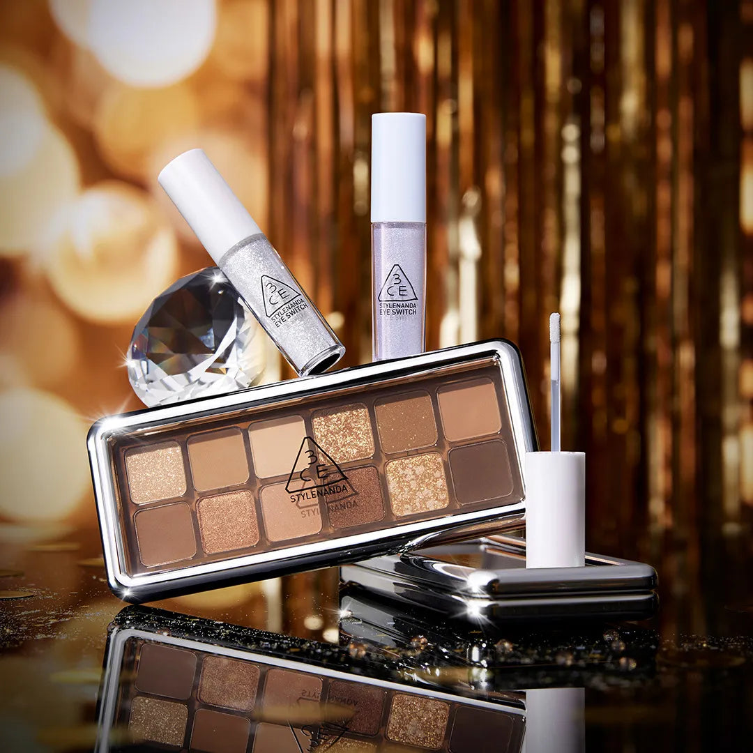 3CE  Eye Switch de 3CE, palette et stick sur fond doré, ambiance maquillage glam