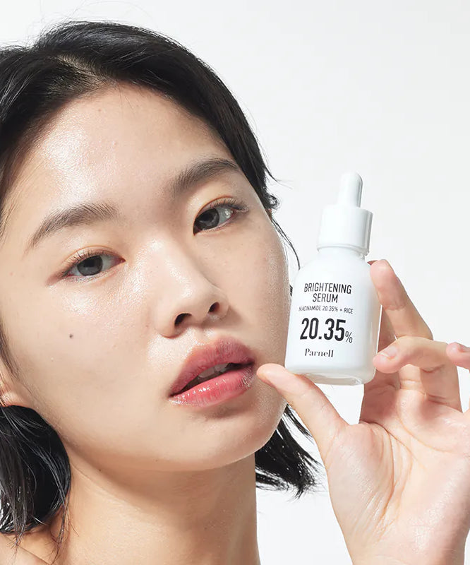 Décris l'image en français: PARNELL  Niacinamide 20.35 Rice Brightening Serum 30ml, sérum lumineux, femme l’applique, flacon blanc.