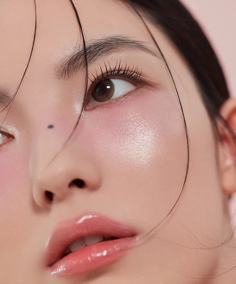 3CE  Blushlighter de la marque 3CE, maquillage visage lumineux, gros plan sur l’étincelle rosée du produit.
