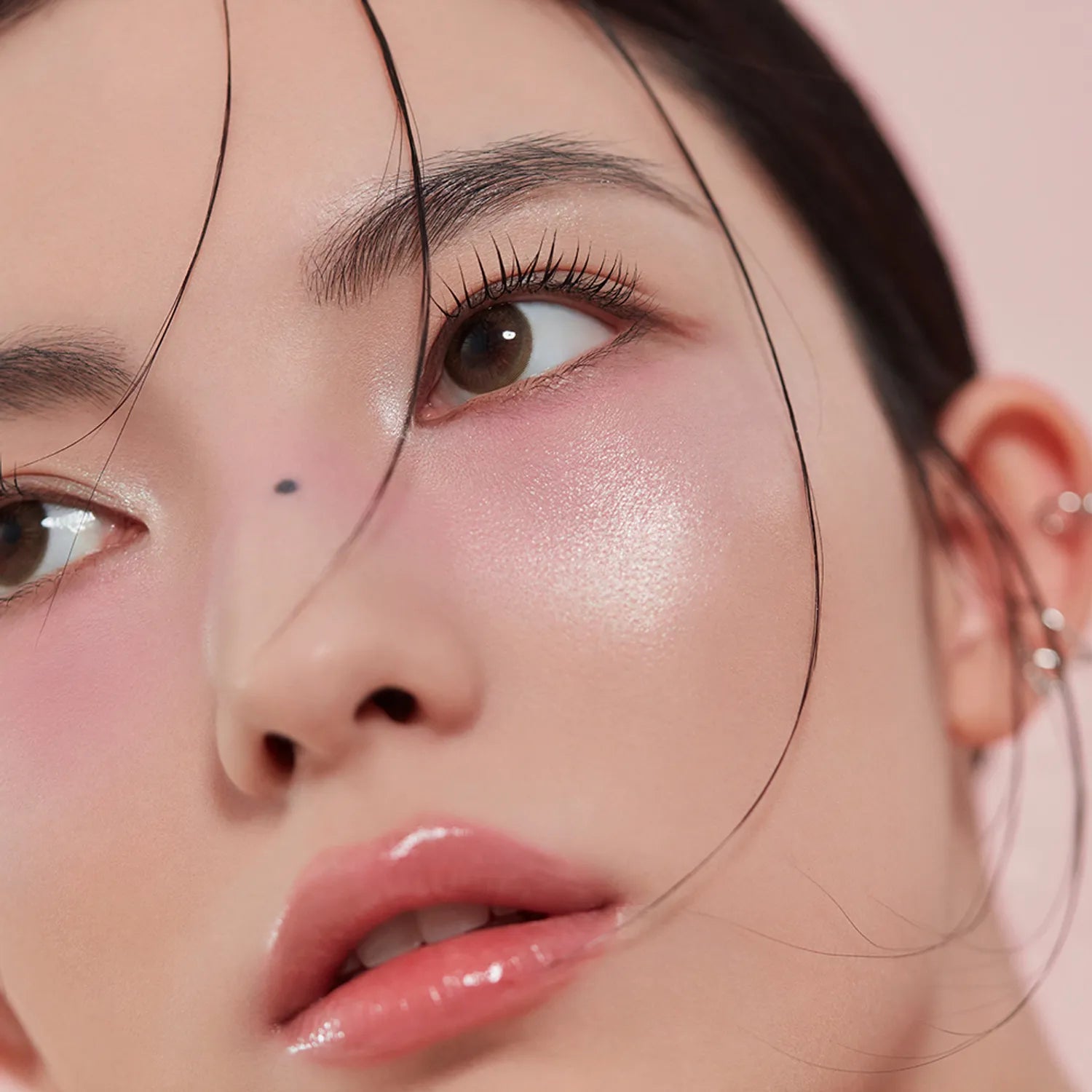 3CE  Blushlighter de la marque 3CE, maquillage visage lumineux, gros plan sur l’étincelle rosée du produit.