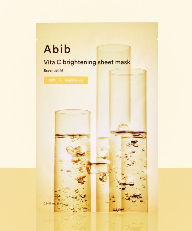 ABIB Essential Fit Vita C Brightening Sheet Mask, pack crème et flacons dorés, gouttes jaunes sur fond clair.