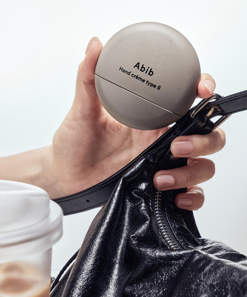 ABIB Hand Cream Type 50ml, crème pour les mains Abib tenue en main, contexte sac en cuir sur fond clair