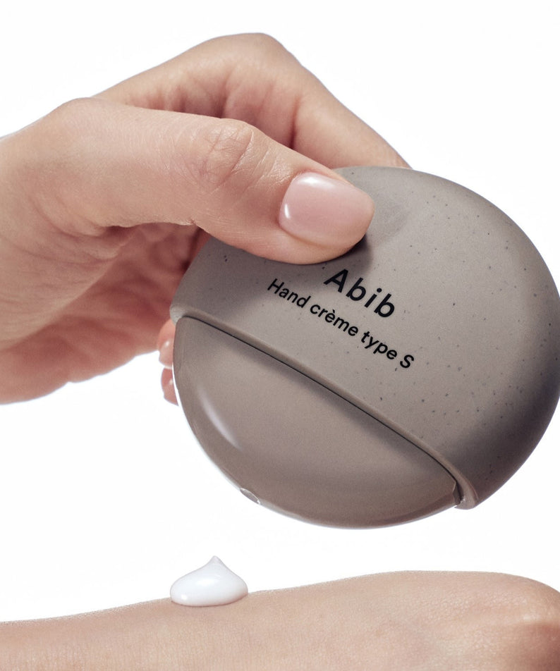 Décris l'image en français : ABIB Hand Cream Type 50ml en main, tube crème hydratante ABIB sur fond blanc.