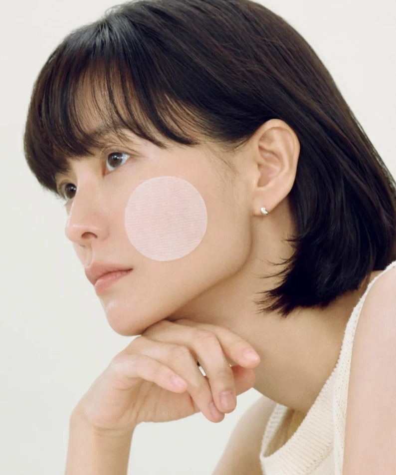 ABIB Heartleaf Spot Pad Calming Touch 70 pads de ABIB, visage féminin avec patch apaisant rond sur la joue, fond clair.