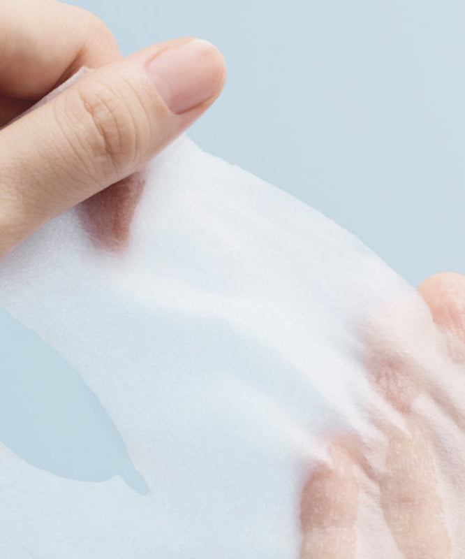 Main appliquant un ABIB  Hyaluronic Acid Moisture Sheet Mask Essential Fit, masque en tissu hydratant, fond bleu clair