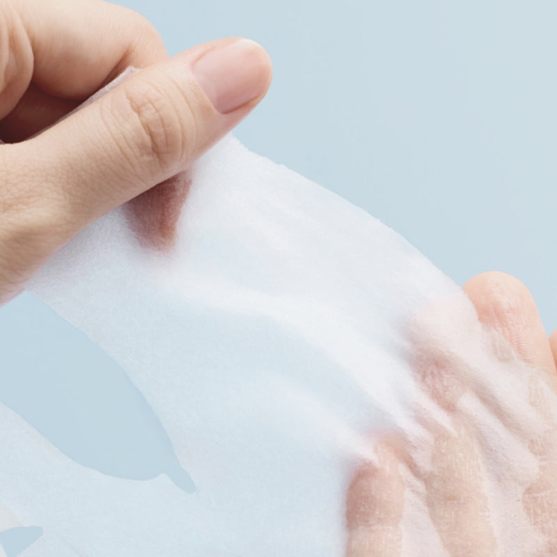 Main appliquant un ABIB  Hyaluronic Acid Moisture Sheet Mask Essential Fit, masque en tissu hydratant, fond bleu clair
