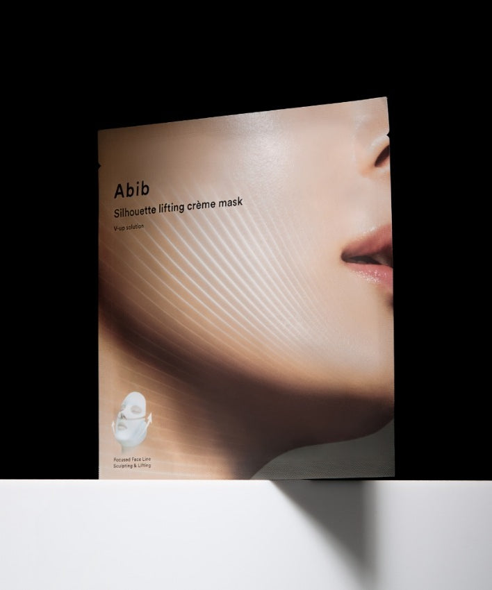 ABIB  Silhouette Lifting Cream Mask V-Up Solution, masque liftant Abib sur visage, packaging sur fond noir, lumière douce.