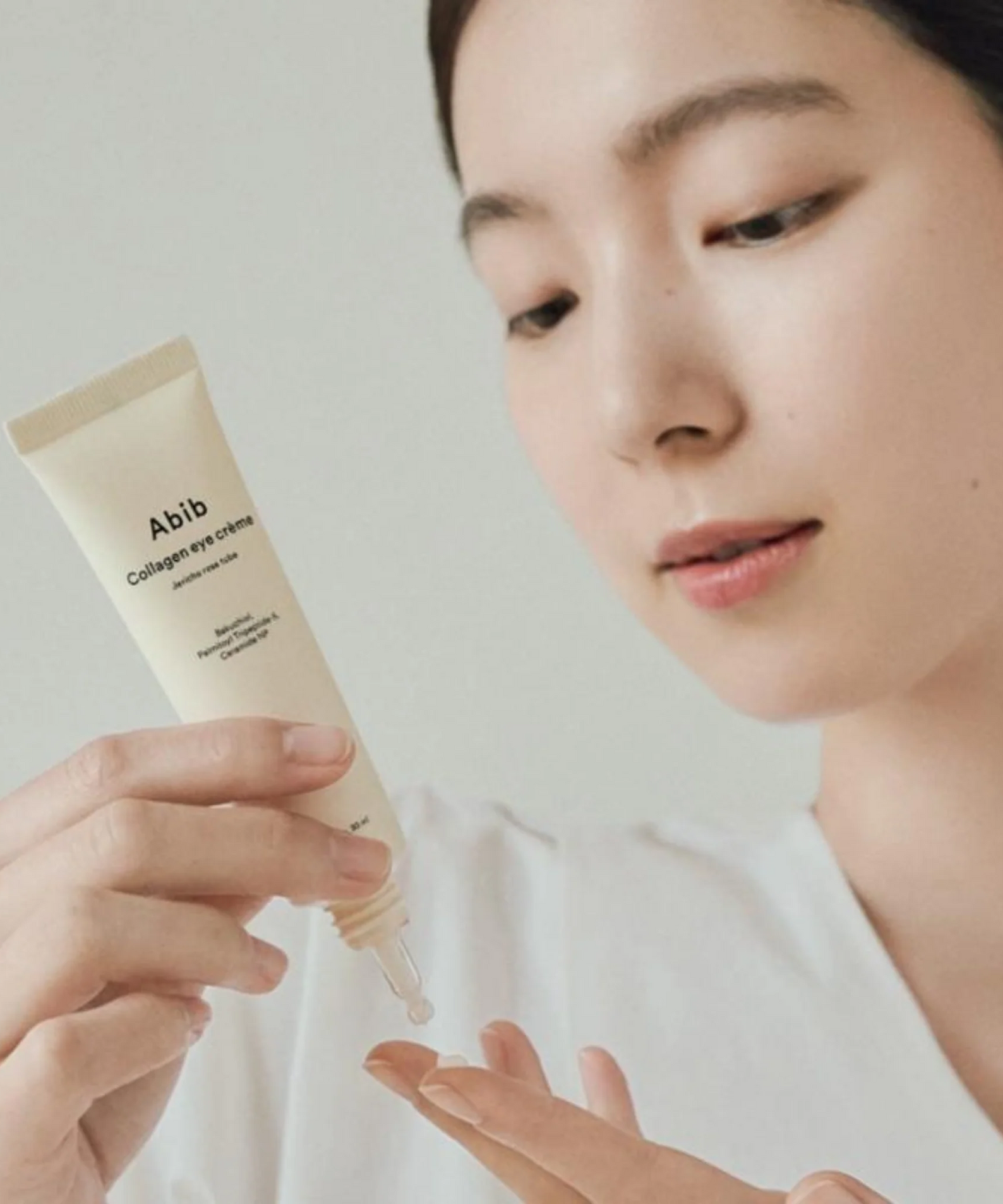 Femme utilisant ABIB Collagen Eye Cream Jericho Rose Tube 30ml pour soin des yeux.