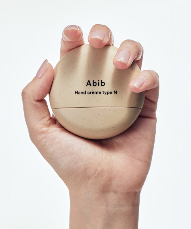 Main tenant le pot de la ABIB Hand Cream 3 Types en main pour une hydratation parfaite.