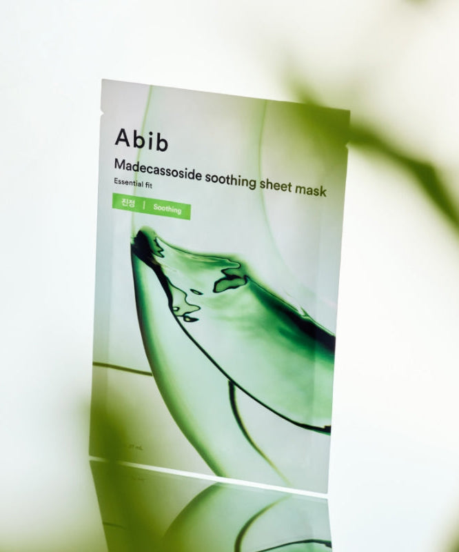 ABIB Madecassoside Soothing Sheet Essential Fit, masque apaisant pour le visage avec madecassoside, pose élégante sur fond vert.