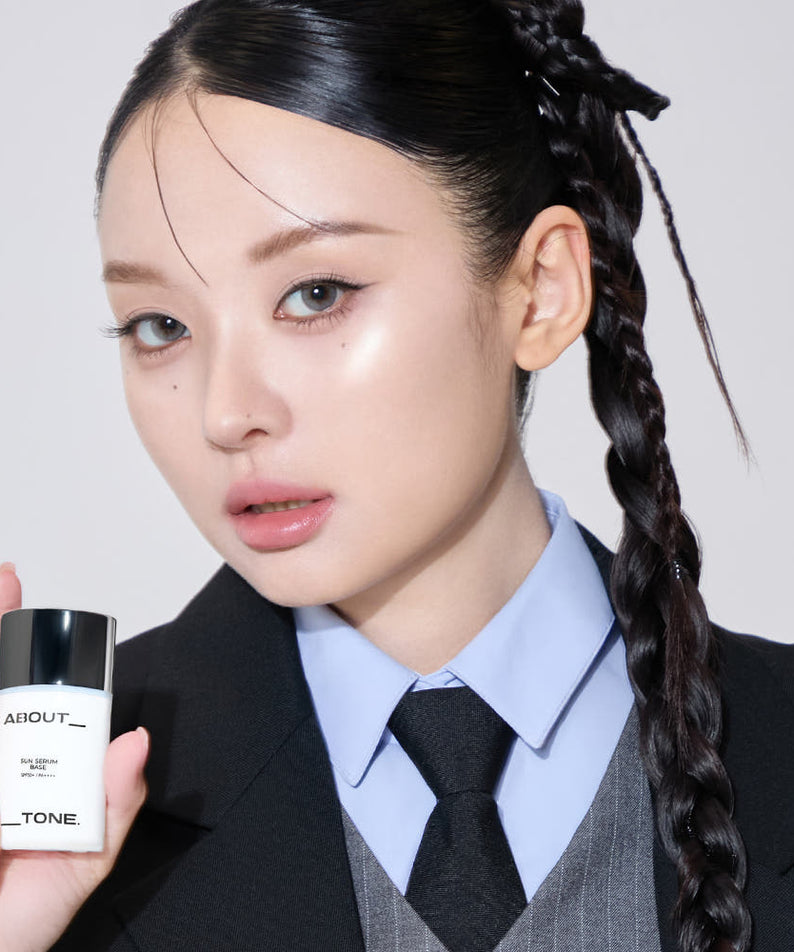 Femme tenant ABOUT TONE Sun Serum Base 30ml (SPF50+, PA++++), soin visage haut de gamme.