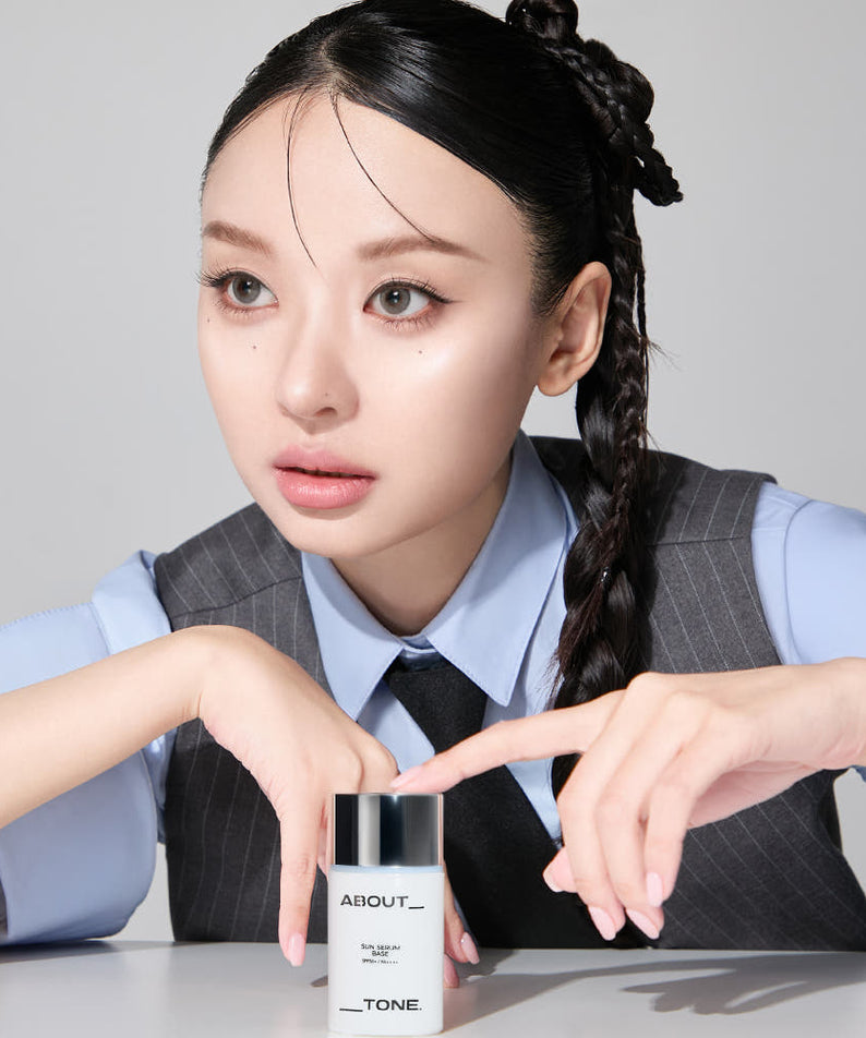 Femme tenant ABOUT TONE Sun Serum Base 30ml (SPF50+, PA++++), soin de la peau protecteur.