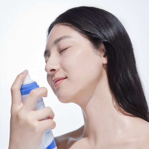 Décris l'image en français : AESTURA  Atobarrier 365 Cream Mist 120ml, femme l’applique sur le visage, contexte soin beauté.