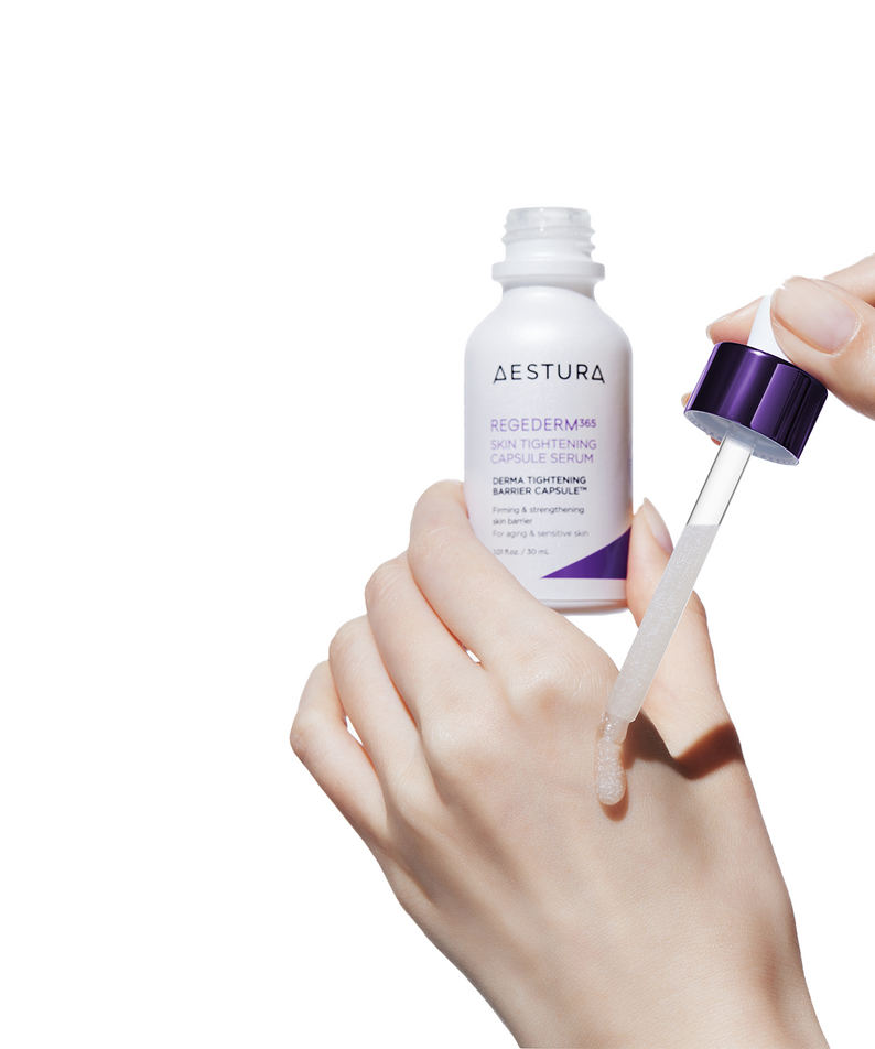 AESTURA Regederm365 Skin Tightening Capsule Serum 30ml, main tenant la pompe, flacon cosmétique blanc sur fond clair.