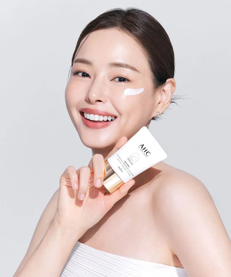 AHC Masters Mela Protect Waterfull Sunscreen 40ml, crème solaire AHC sur peau, femme souriante studio blanc.