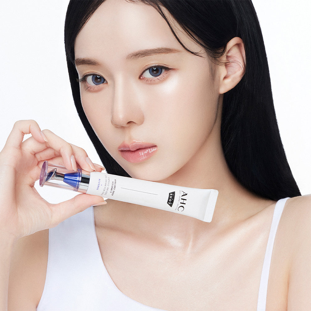 Décris l'image en français: AHC Proshot Hyaluro Deep Volume 5 Capsule Eye Cream for Face 30ml, femme appliquant crème yeux AHC.