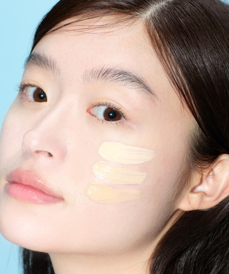 Femme appliquant ALTERNATIVE STEREO Soap Nude Cushion SPF42 PA++ sur la joue, démontrant des nuances de fond de teint.