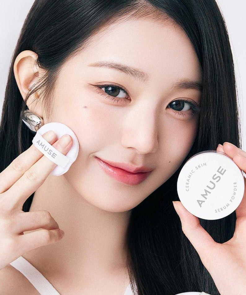 Femme utilisant AMUSE Ceramic Sebum Powder, maquillage léger, peau lisse et éclatante. Produit cosmétique tendance.