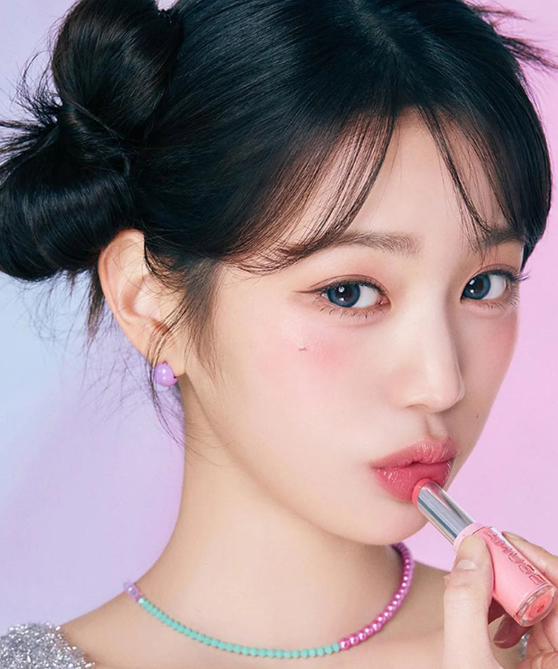 Femme appliquant AMUSE Fondue Balm, un baume à lèvres hydratant, pour un look élégant et glamour.