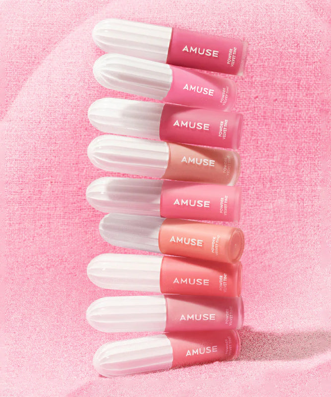 Collection de teintes AMUSE Powder Velvet Tint sur fond rose texturé.