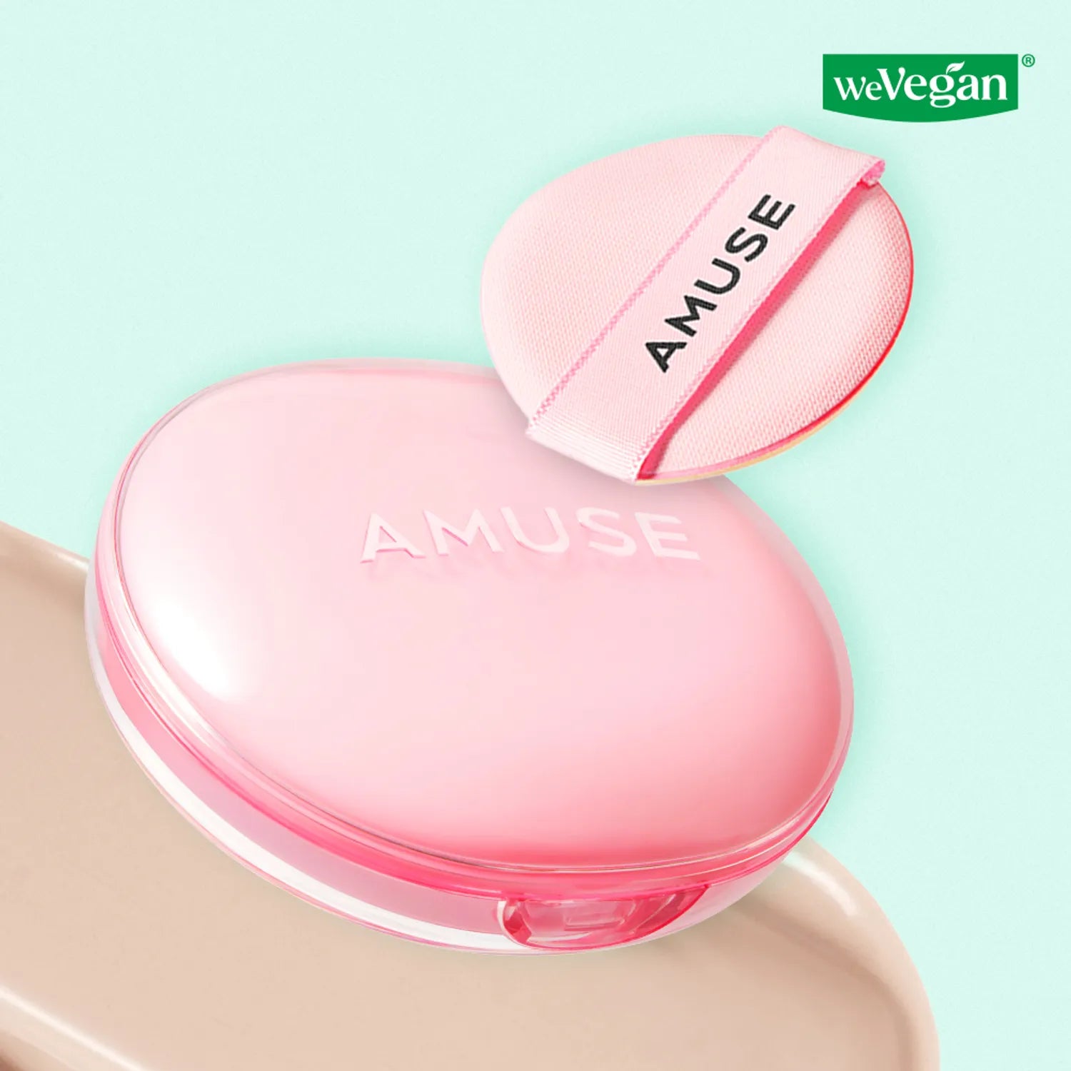 AMUSE Dew Power Vegan Cushion de la marque AMUSE, coussin rose sur fond turquoise, logo WeVegan.