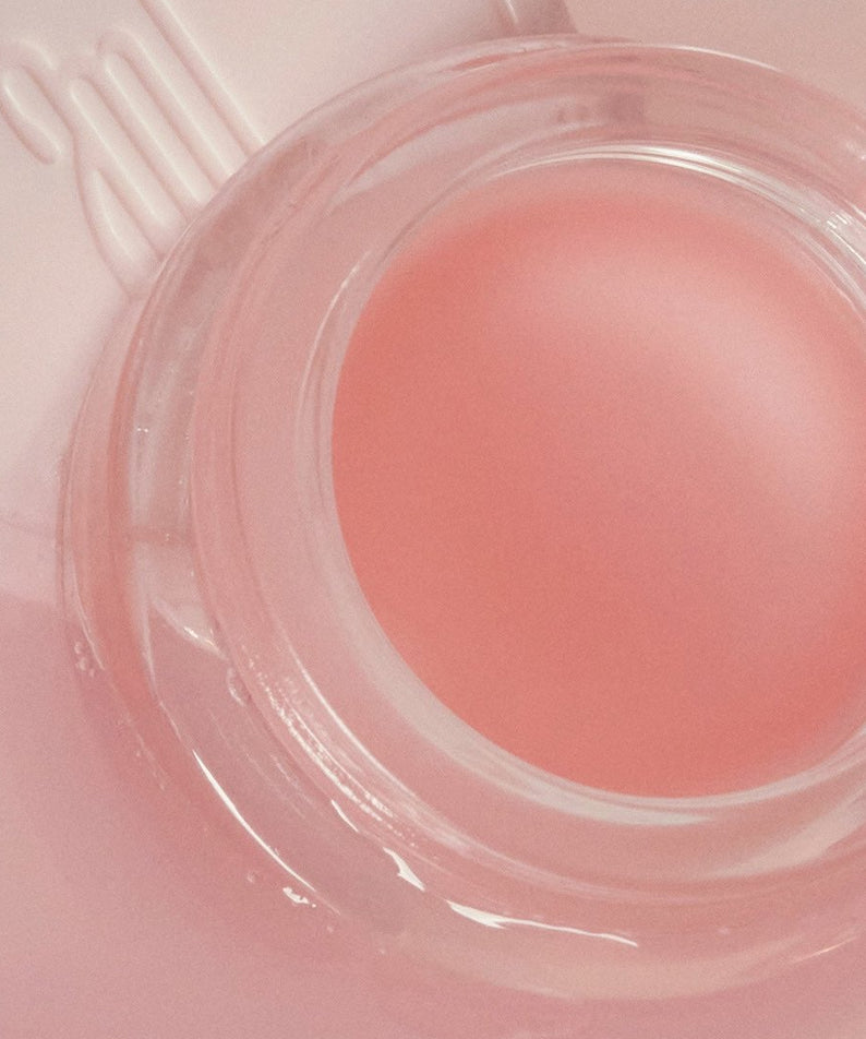 ANILLO Mellow Glow Balm, baume lumineux rose en pot transparent sur fond pastel, visuel esthétique beauté.