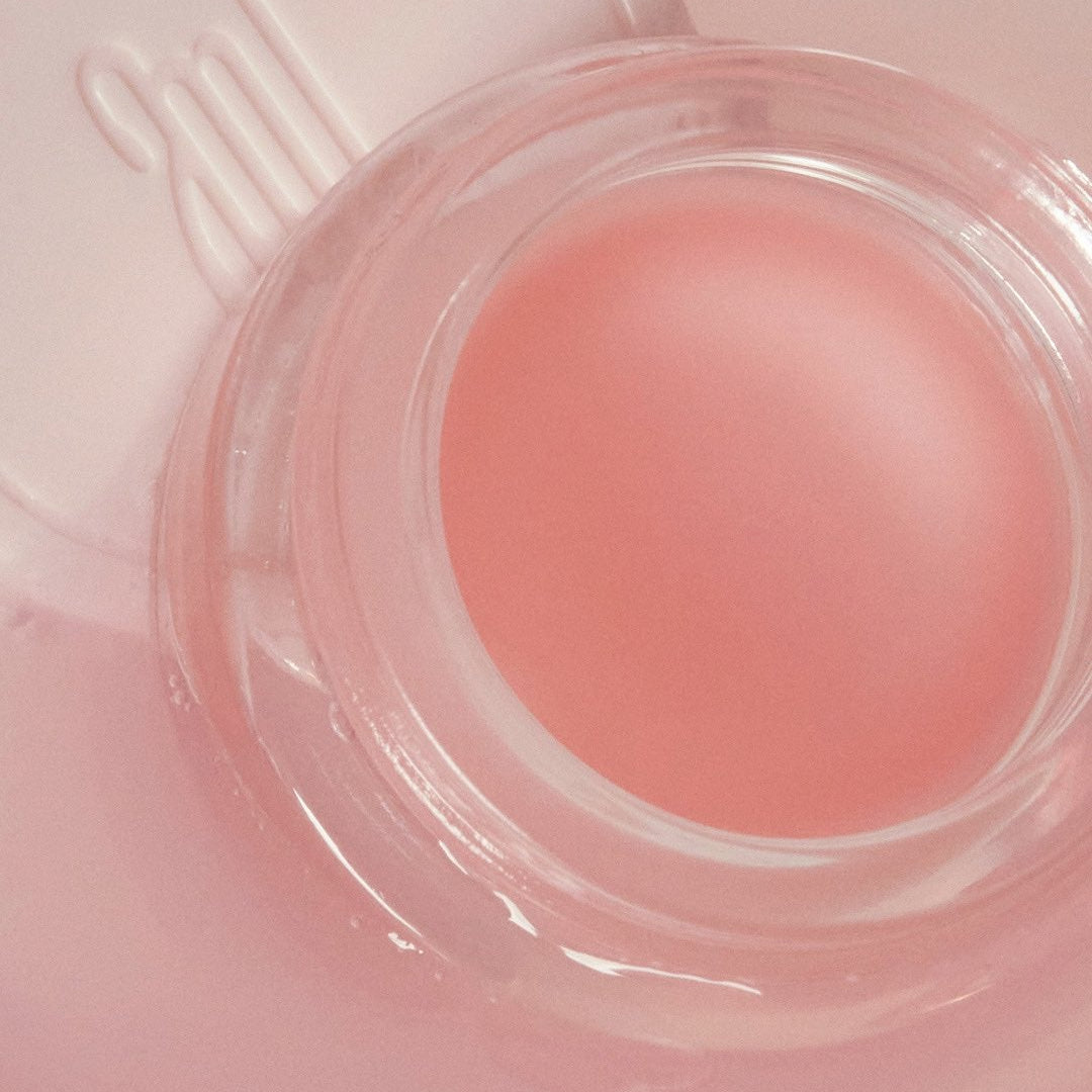ANILLO Mellow Glow Balm, baume lumineux rose en pot transparent sur fond pastel, visuel esthétique beauté.
