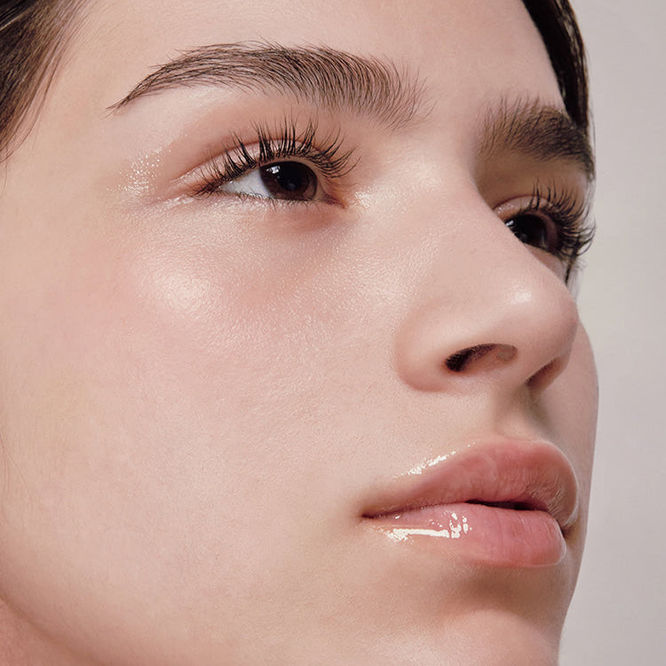 ANILLO Mellow Glow Balm : baume lissant sur le visage, éclat doux, gros plan maquillage, peau lumineuse.