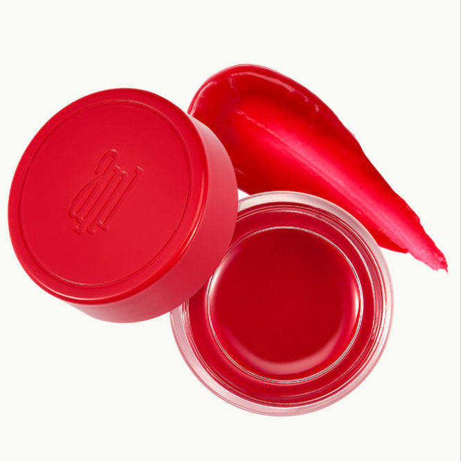 ANILLO Petal Glow Balm, baume brillant de la marque ANILLO en flacon rouge ouvert, texture pétale sur fond clair.