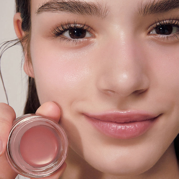 Décris l'image en français : ANILLO Rose Glow Balm, baume rosé sur lèvres, maquillage lumineux, gros plan visage