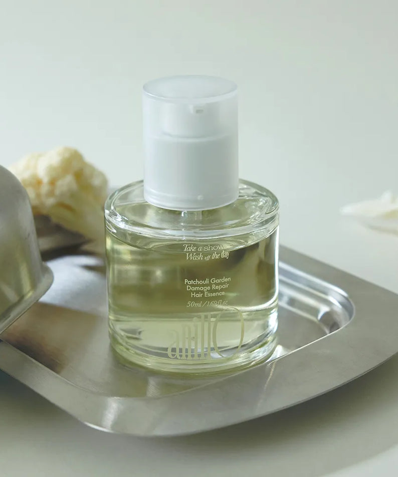 ANILLO Patchouli Garden Damage Repair Hair Essence 50ml, flacon sur plateau en métal, contexte salle de bain, fond clair.