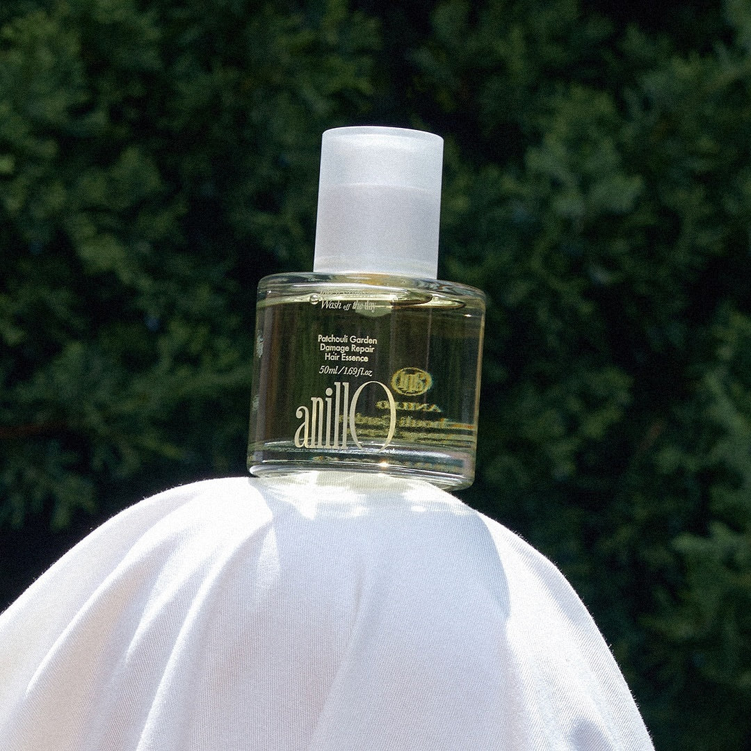 ANILLO Patchouli Garden Damage Repair Hair Essence 50ml, flacon vert sur fond jardin, marque ANILLO, cheveux réparation