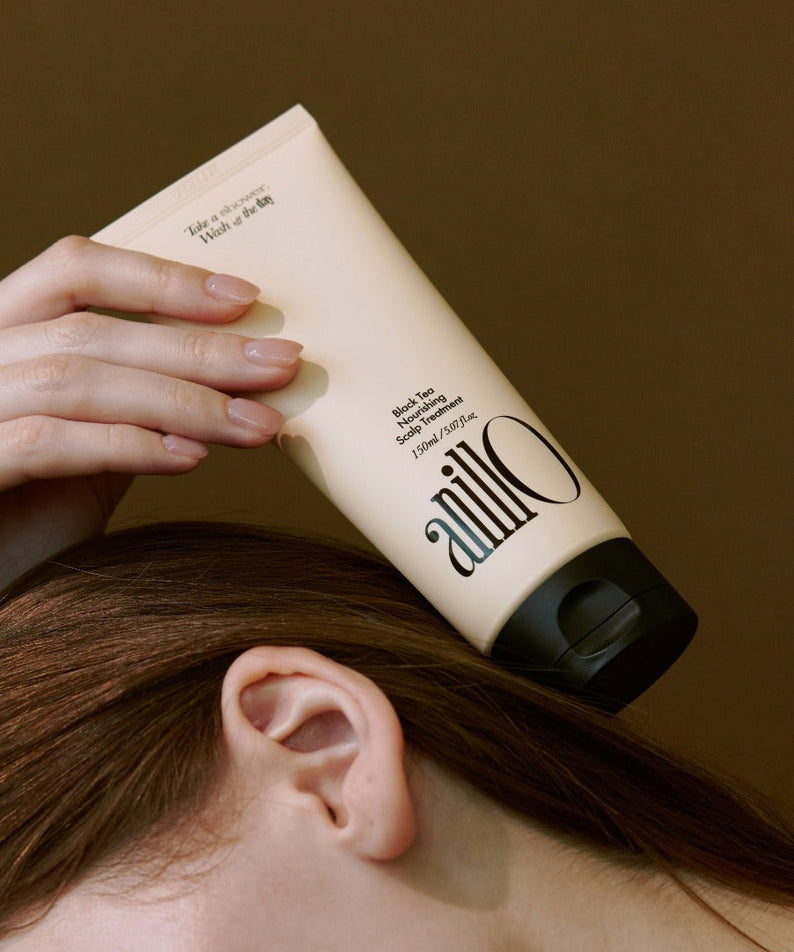 ANILLO Black Tea Nourishing Scalp Treatment 150ml sur une tête, mains appliquant le produit, contexte beauté.