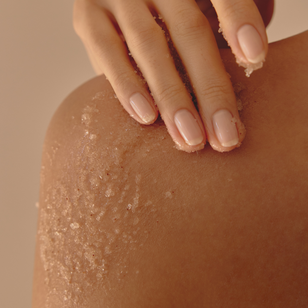 ANILLO Fig Whisky Body Scrub 240g, exfoliation sur peau avec mains, texture granuleuse, ambiance spa visuel