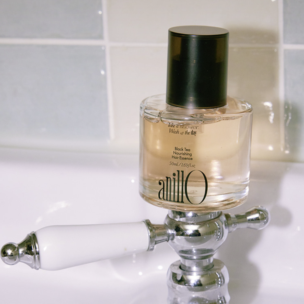 ANILLO Black Tea Nourishing Hair Essence 50ml : flacon sur support chromé, salle de bain lumineuse, esthétique premium.