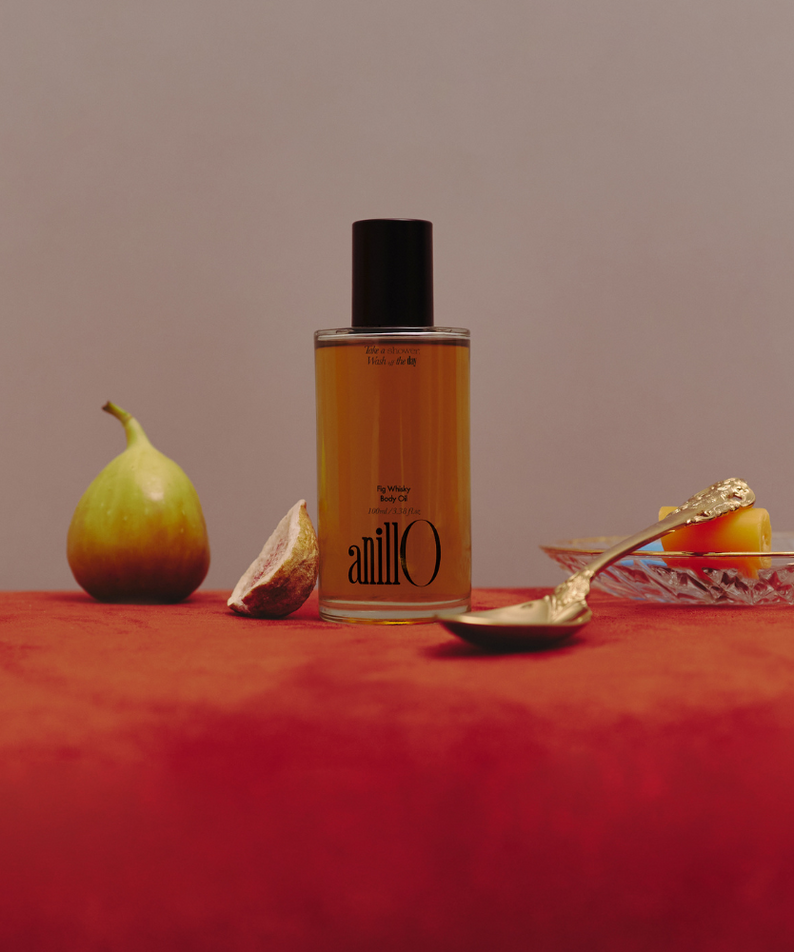ANILLO Fig Whisky Body Oil 100ml, bouteille sur fond beige avec figues et ambiance spa, marque ANILLO, scène visuelle