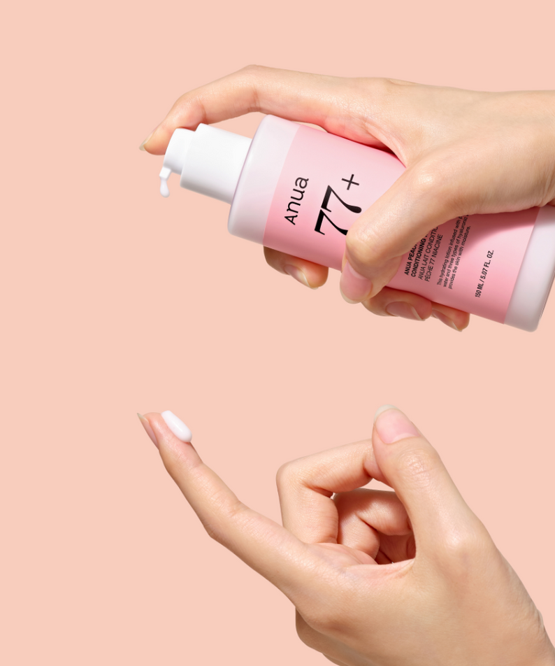 Décris l'image en français : ANUA Peach 77 + Niacin Conditioning Milk 150ml de la marque ANUA, mains appliquant sur peau.