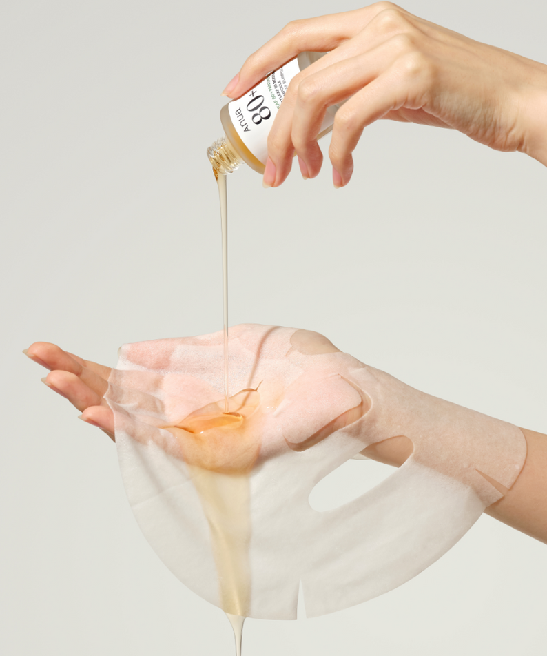 ANUA Heartleaf 80 + Panthenol Moisture Soothing Ampoule Mask, main appliquant une ampoule sur un masque en tissu, visage.