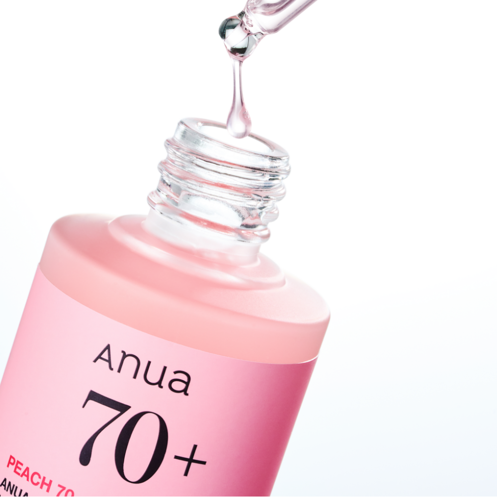 ANUA Peach 70 + Niacin Serum 30ml d’Anua, flacon rose avec sérum coulant, arrière-plan blanc, gouttes brillantes.