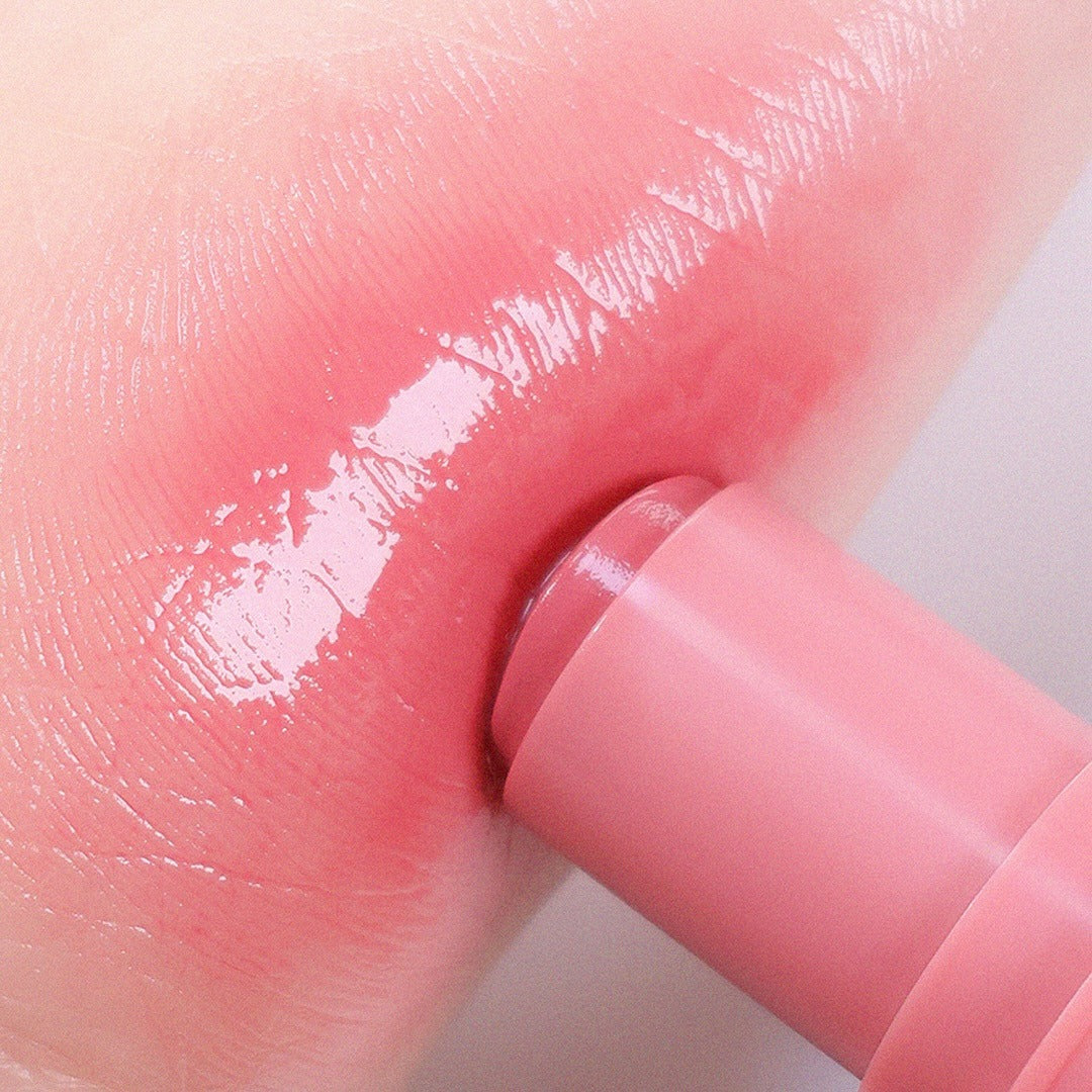 AOU Dewy Bar, produit de la marque AOU, sur peau rose avec applicateur, contexte visuel dégradé et lumineux.