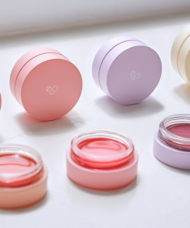 Baumes AOU Glowy Tint Balm colorés avec couvercles pastel, essentiels beauté pour un teint lumineux.