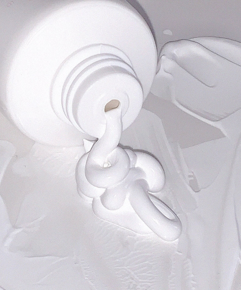 Crème AOU Tone-Up Dazzling Cream étalée sur une surface, montrant sa texture onctueuse et éclatante.