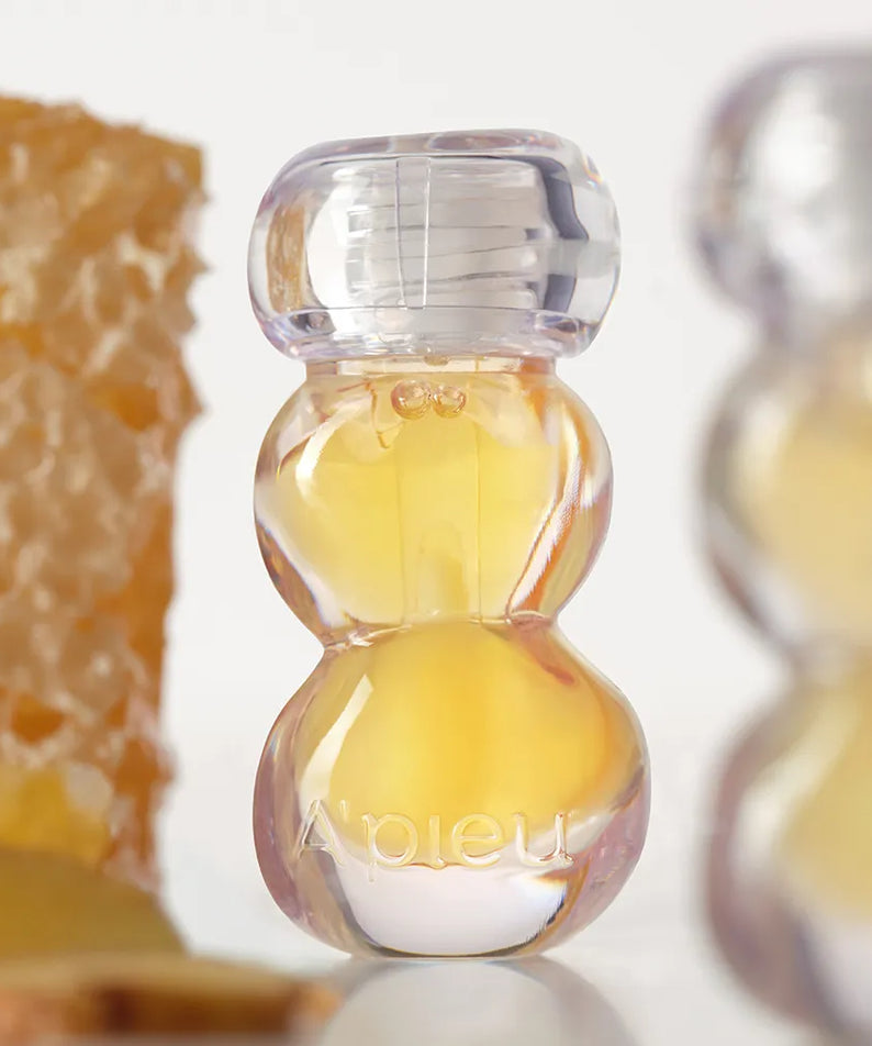 A'PIEU Jelly Honey Lip Oil 4g, branding en français sur flacon gouttes miel, gros plan décor miel, fond clair