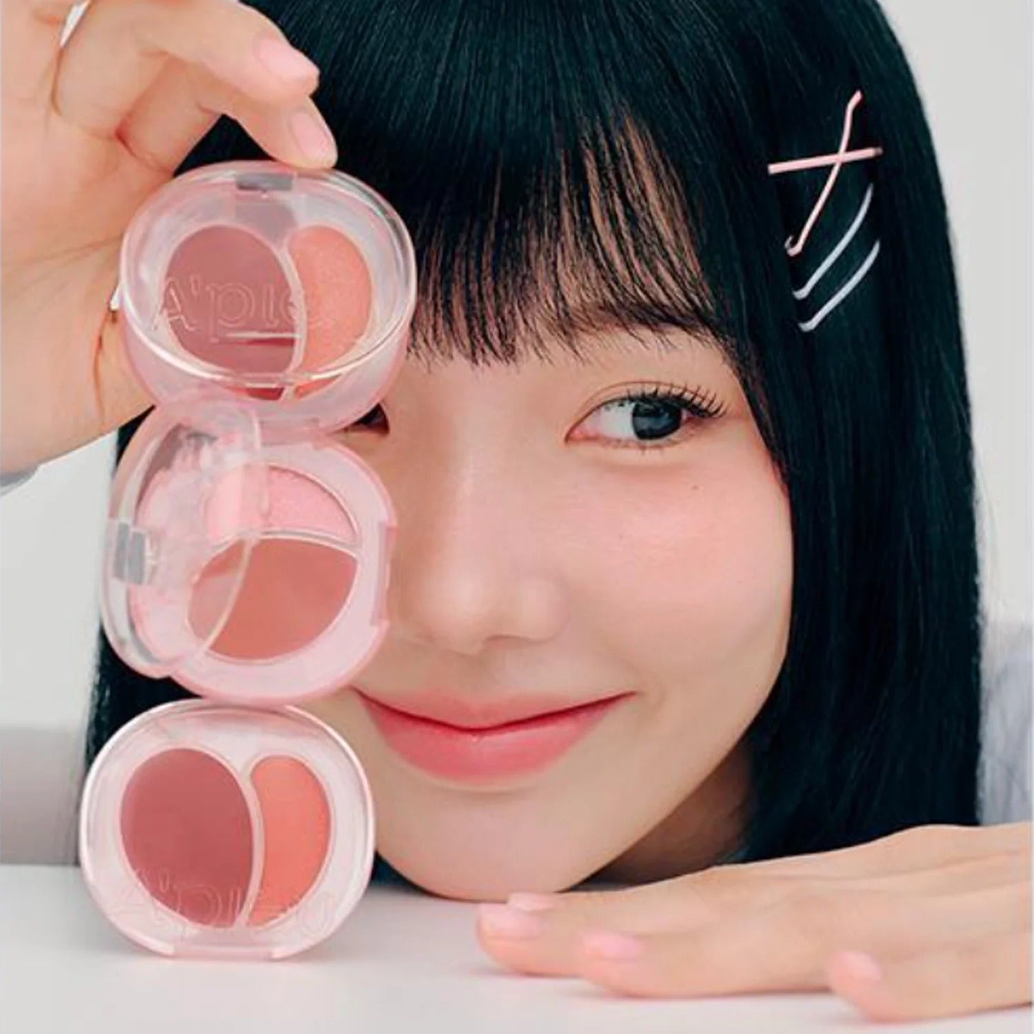 A'PIEU Juicy Pang Mood Blending Lip & Cheek Balm A'PIEU, palette rose maquillage sur fond blanc, main et visage