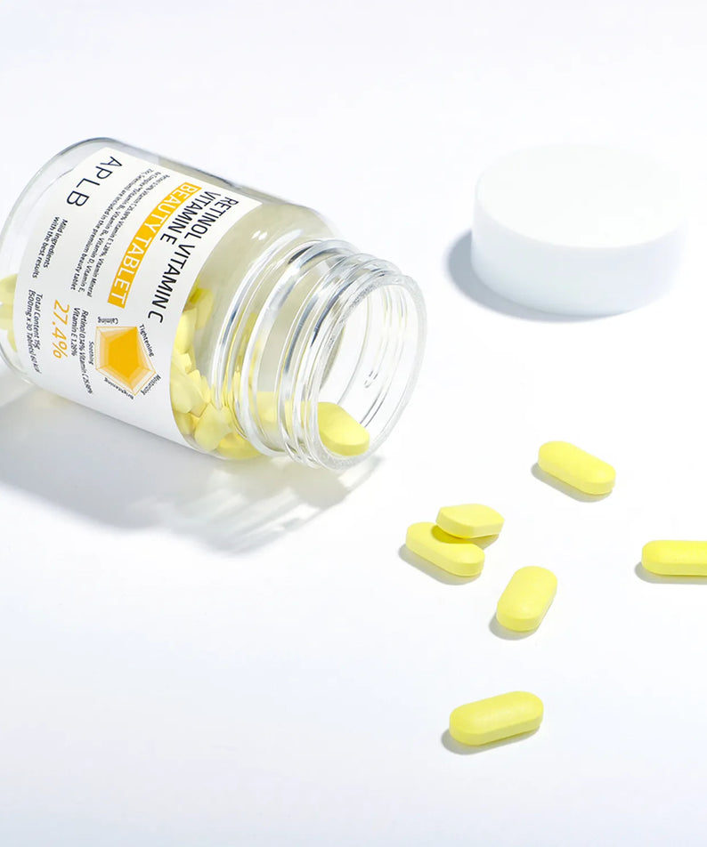 APLb Retinol Vitamin C Vitamin E Beauty Tablet APLB, comprimés jaunes sur fond blanc, flacon posé avec poudrier blanc