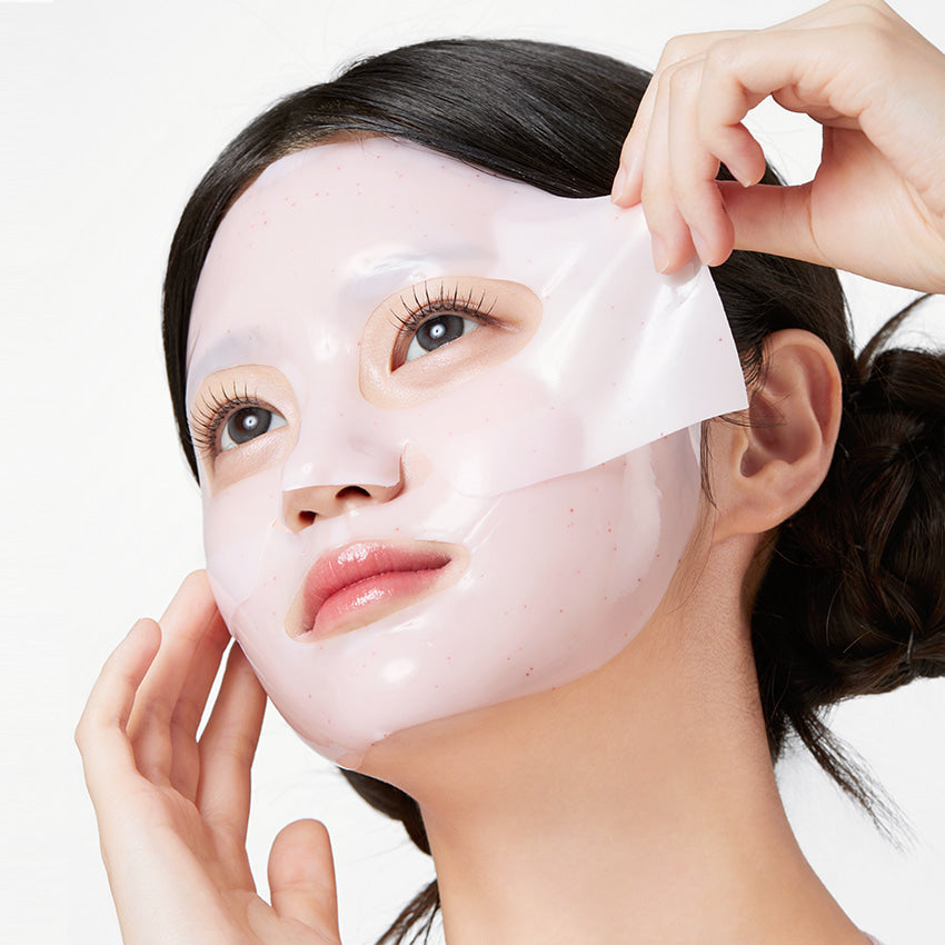APRILSKIN TXA Niacinamide Collagen 99 Capsule Gel Mask 4 Sheets : femme applique un masque gel sur le visage, mains visibles.