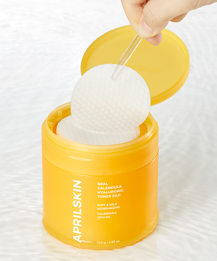 APRILSKIN Calendula Hyaluronic Toner Pad : main retire un pad du pot jaune, marque sur l’étiquette, contexte soin visage