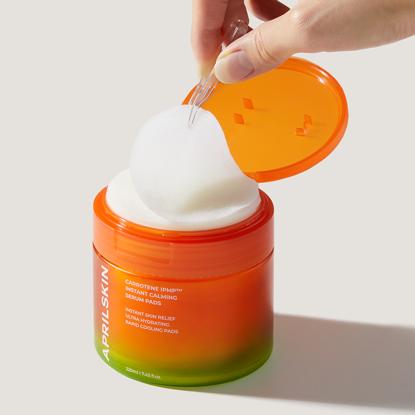 APRILSKIN Carrotene IPMP Inatant Calming Serum Pad, marque APRIL SKIN : pad sur pot orange, usage apaisant sur main